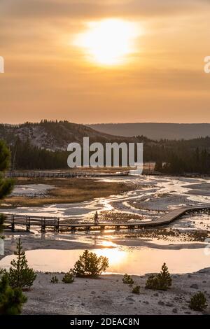 A hazy sunset over the Porcelain Basin in the Norris Geyser Basin in Yellowstone National Park, Wyoming, USA. Stock Photo