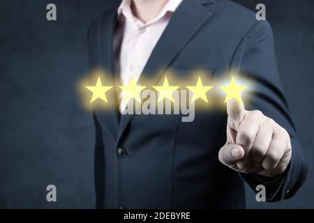 Businessman giving a five star rating. Businessman pointing five star visual symbol to increase rating of company. Five Stars Rating - Satisfaction Fe Stock Photo