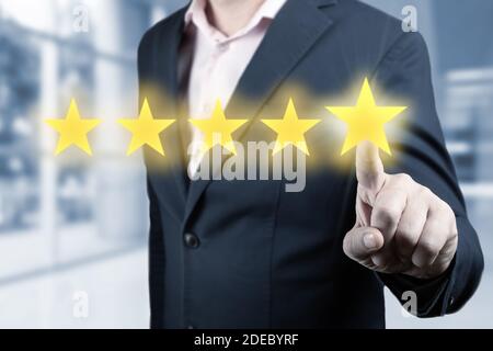 Businessman hand touching five star symbol. Man Is Pointing Five Stars - Review And Rating Concept. Person Pointing On 5 Star Review, Costumer Feedbac Stock Photo