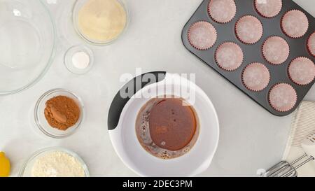 Chocolate muffins recipe. Mixing together cup of coffee, cooking oil and vanilla Stock Photo