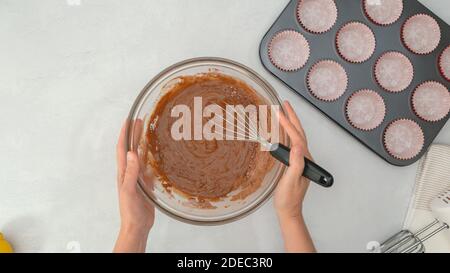 Chocolate muffins recipe. Whisk the wet ingredients into the dry ingredients, mixing muffin batter Stock Photo
