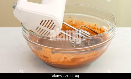 Chocolate cake batter in a glass bowl, and an electric mixer close up Stock Photo