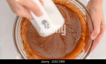 Mixing chocolate batter using an electric mixer. Chocolate muffins or chocolate cupcakes recipe Stock Photo