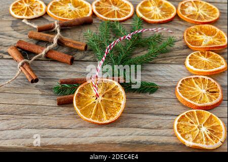 Christmas handmade natural decorations. Garland and fir tree toy made of dried slices of oranges on wooden table. Winter still life composition Stock Photo