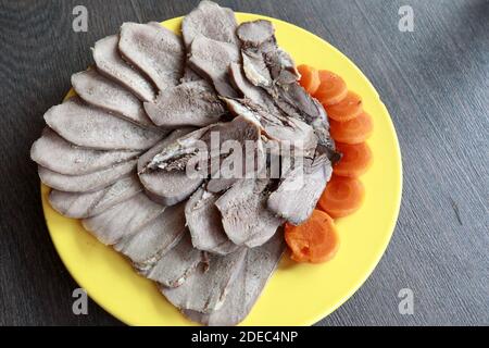 Slices of boiled tongue on yellow plate Stock Photo