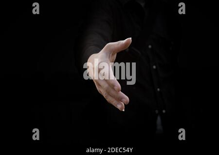 Businessman offer hand for handshake and cooperation over black background. Business deal proposal concept. Stock Photo