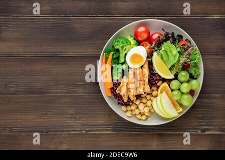 Clean healthy low fat ready to eat food with mixed vegetable and fruit salad in round shape dish on wood table background top view with copy space Stock Photo