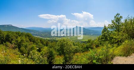 A huge white cloud in the blue sky over the valley in a mountainous region. View from viewpoint on the village Kamennomostsky, the Republic of Adygea, Stock Photo