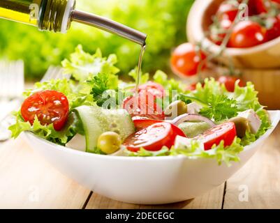 olive oil pouring into bowl of salad Stock Photo