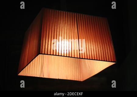 Close-up of modern chandelier hanging under ceiling in dark room. Stock Photo