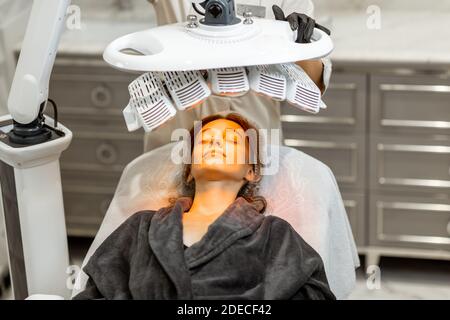 Portrait of a young woman doing led light therapy on her face at luxury medical office Stock Photo