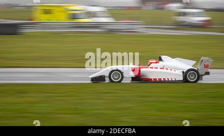 A panning shot of a racing car as it circuits a track. Stock Photo