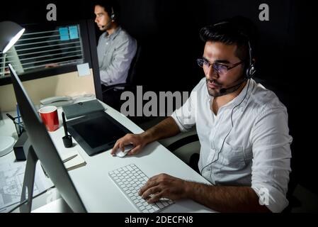 Asian technical support team working night shift in call center office talking with customers in different time zone Stock Photo