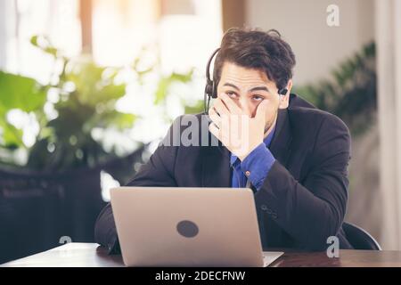 Asian businessman have action with a tired expression between using computer laptop. he cover face with hand upset from work in front of. Stock Photo