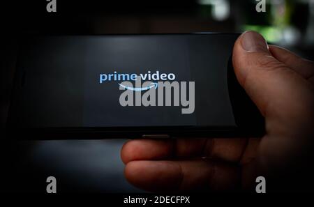 Hand holding a mobile phone with a Amazon prime video logo displayed on the screen to illustrate streaming services. Stock Photo