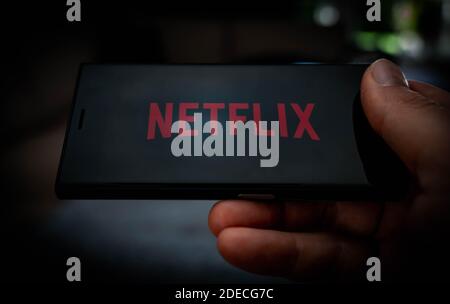 Hand holding a mobile phone with a Netflix logo displayed on the screen to illustrate streaming services. High quality photo Stock Photo