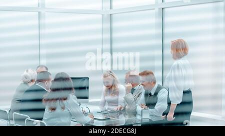through the blinds. business team is discussing something at a working meeting. Stock Photo