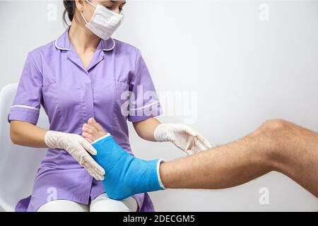 Close up of a man's leg in a cast and a blue splint after bandaging in a hospital. Stock Photo