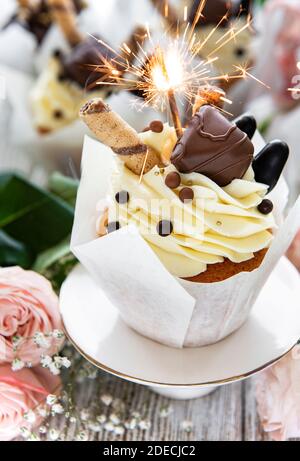 Chocolate cupcakes with burning sparklers on white wooden background Stock Photo