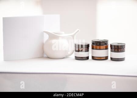 Composition of a glass bottles with empty stickers to copy paste and teapot on the white background Stock Photo