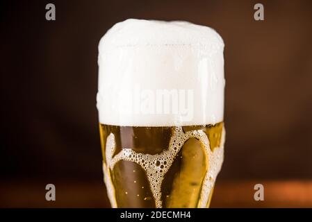 Golden cold beer in the glass on the table with overyflow frothy foam Stock Photo