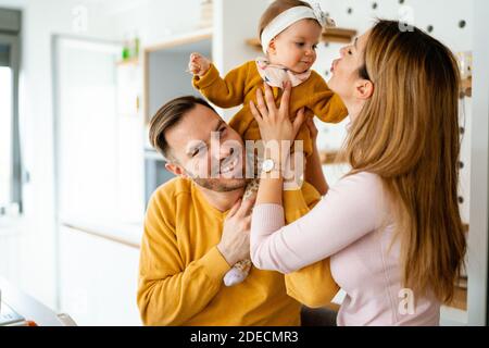 Happy family mother and father playing with a baby at home