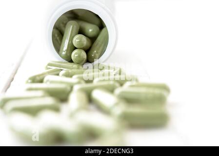 Close up of organic natural green Asian Kariyat plant herbal medicine in form of capsules spillig out of the bottle Stock Photo