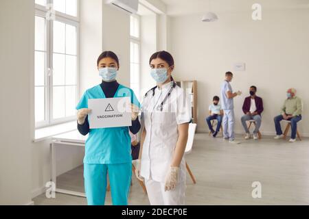 Young doctors in medical face masks promoting vaccination campaign that saves lives Stock Photo