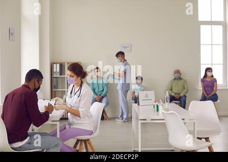 Doctor of modern clinic talking to patient before giving him an antiviral injection Stock Photo