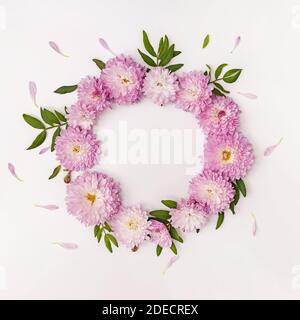 Floral frame made with pink flowers, green leaves and petals Stock Photo