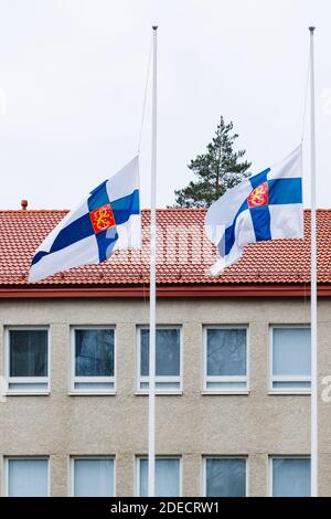Two finnish flags lowered to half mast on the occasion of mourning at cloudy autumn day Stock Photo