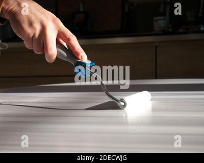 Close-up on the hand of a man doing DIY, painting a piece of furniture with a brush Stock Photo