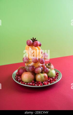 Alternative to The Christmas tree vegan tree made of fruit on a colored background .The concept of Christmas. Stock Photo