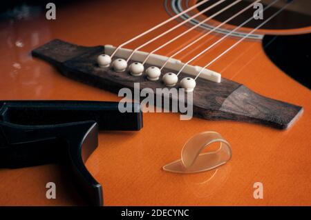 Fingerpick guitar concept: a thumb pick and a guitar capo laying on acoustic guitar Stock Photo