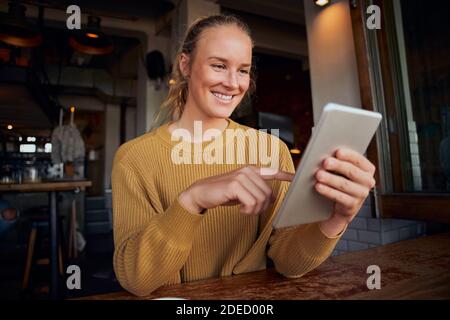 Woman using digital tablet sitting and relaxing in modern cafe Stock Photo