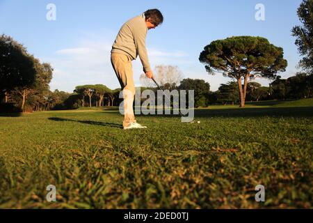 man playing golf in the course hitting the ball with swing Stock Photo