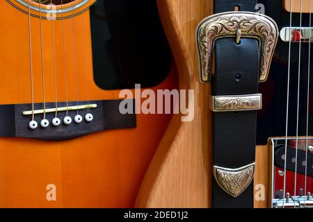 Acoustic and electric guitars and leather strap with silver buckle close-up. Stock Photo