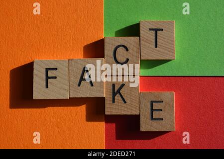 Fact, Fake, words in wooden alphabet letters on red, orange and green background Stock Photo