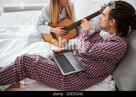 Handsome young man teaching girlfriend to play guitar Stock Photo