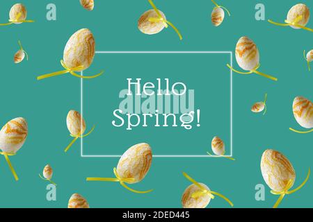 Hello spring hand lettering. Winter pattern with flying yellow eggs on turquoise background. Zero gravity concept. Stock Photo