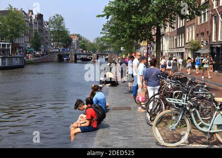 AMSTERDAM, NETHERLANDS - JULY 7, 2017: People visit Prinsengracht canal in Amsterdam, Netherlands. Amsterdam is the capital city of The Netherlands. Stock Photo