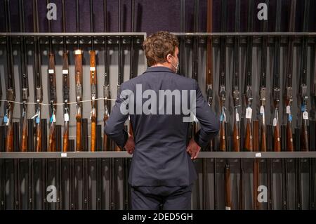 Knightsbridge, London, UK. 30th Nov, 2020. Preview of Bonhams' Antique Arms, Modern Sporting Guns & Exceptional Firearms sale in London. The sale will be held on 3 December. Image: Bonhams staff member looks along racks of shotguns on display for the sale. Credit: Malcolm Park/Alamy Live News Stock Photo