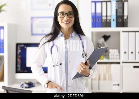 Portrait of smiling female doctor in white coat in medical office Stock Photo