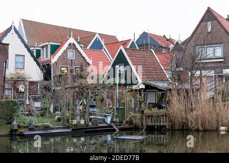 Dutch houses on water channel. A fishing village with vintage northern Netherlands houses with orange tile roofs. Backyard in front of pond. Volendam Stock Photo