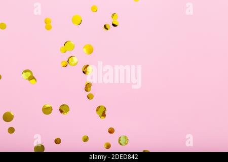 Gold confetti sparkles frame on pink background. Flat lay, top view festive backdrop with copy space. Celebration concept. Stock Photo