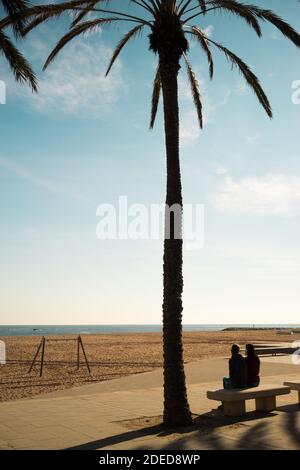 silhouette of two women sitting on a beach back Stock Photo