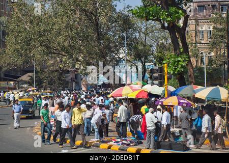 A colourful street scene in Mumbai India with market stalls and large crowds of people plus colourful sun brollies and trees Stock Photo