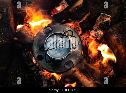 Kettle boiling water on a hot camp fire, seem from the top down. Close up. . High quality photo Stock Photo