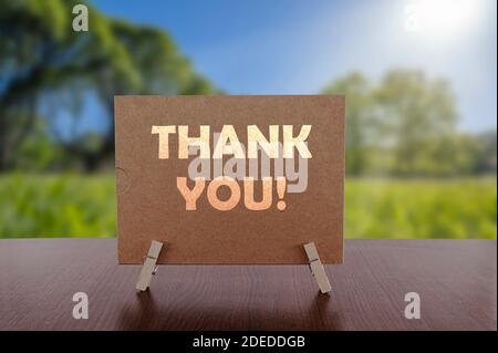 Thank you card on the table with sunny green park background. Stock Photo