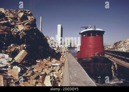 1970s Photo - (1973) -  Tugboat herds two laden garbage scows down the East River from transfer point at 91st Street. Stock Photo